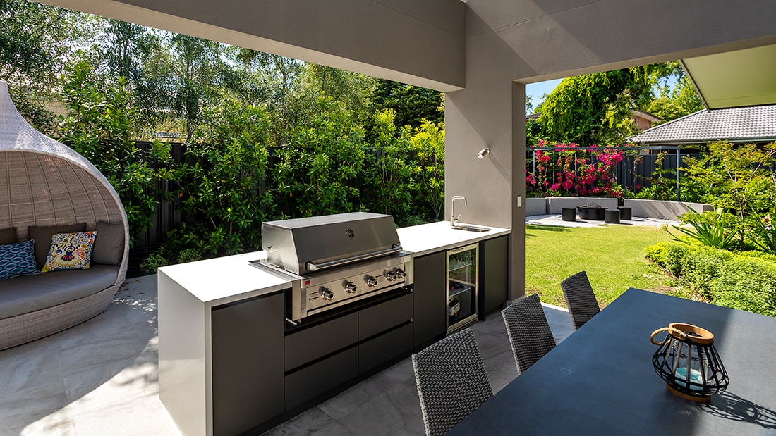An outdoor kitchen and barbecue in a large landscaped garden