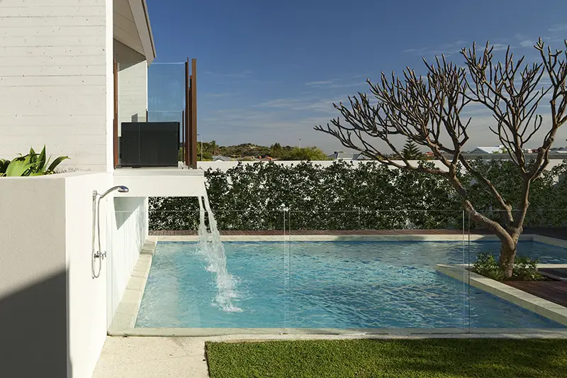 concrete pool with glass fence, timber decking and waterfall